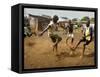 Young Children Play Soccer on a Dirt Pitch by the Side of Railway Tracks-null-Framed Stretched Canvas