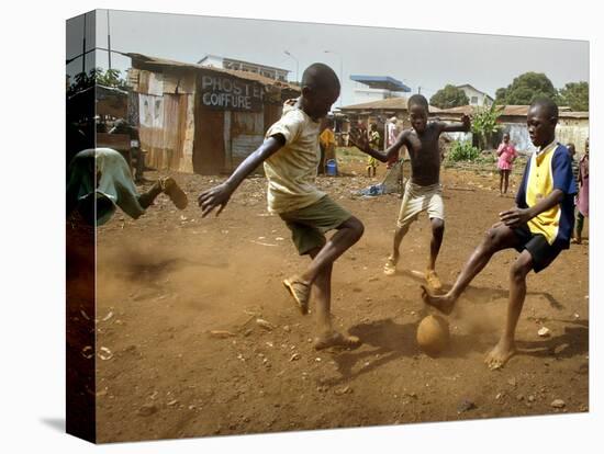 Young Children Play Soccer on a Dirt Pitch by the Side of Railway Tracks-null-Stretched Canvas