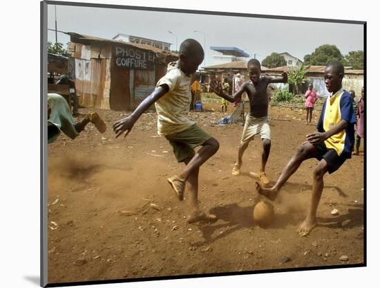 Young Children Play Soccer on a Dirt Pitch by the Side of Railway Tracks-null-Mounted Photographic Print