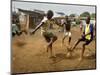 Young Children Play Soccer on a Dirt Pitch by the Side of Railway Tracks-null-Mounted Photographic Print