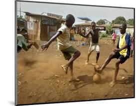 Young Children Play Soccer on a Dirt Pitch by the Side of Railway Tracks-null-Mounted Photographic Print