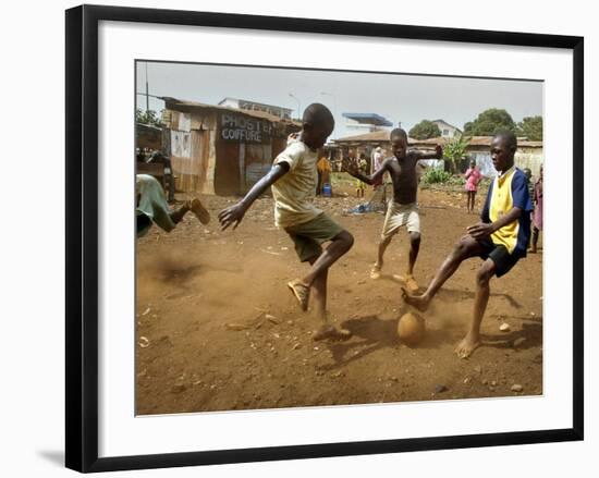 Young Children Play Soccer on a Dirt Pitch by the Side of Railway Tracks-null-Framed Photographic Print