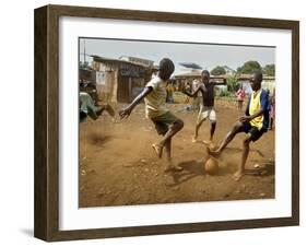 Young Children Play Soccer on a Dirt Pitch by the Side of Railway Tracks-null-Framed Photographic Print