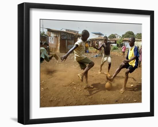 Young Children Play Soccer on a Dirt Pitch by the Side of Railway Tracks-null-Framed Photographic Print