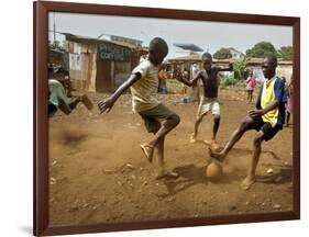 Young Children Play Soccer on a Dirt Pitch by the Side of Railway Tracks-null-Framed Photographic Print