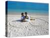 Young Couple on Beach Sitting in a Heart Shaped Imprint on the Sand, Maldives, Indian Ocean, Asia-Sakis Papadopoulos-Stretched Canvas