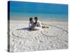 Young Couple on Beach Sitting in a Heart Shaped Imprint on the Sand, Maldives, Indian Ocean, Asia-Sakis Papadopoulos-Stretched Canvas