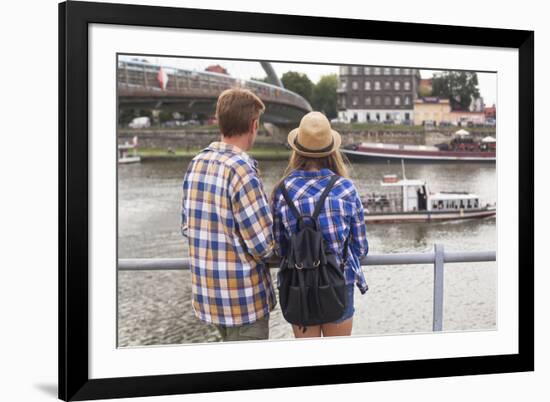 Young Couple on the River Bank in a European City (Rear View) Romantic Journey.-De Visu-Framed Photographic Print