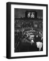 Young Couple Snuggling in Convertible as They Watch Large Screen Action at a Drive-In Movie Theater-J^ R^ Eyerman-Framed Photographic Print