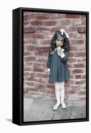Young Girl Standing in Front of a Stone Wall Smelling a Flower.-Nora Hernandez-Framed Stretched Canvas
