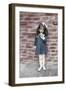 Young Girl Standing in Front of a Stone Wall Smelling a Flower.-Nora Hernandez-Framed Giclee Print