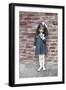 Young Girl Standing in Front of a Stone Wall Smelling a Flower.-Nora Hernandez-Framed Giclee Print