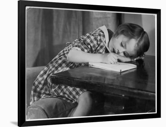 Young Girl Writes on Paper with a Pencil-null-Framed Art Print