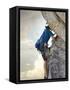 Young man rock climbing up a vertical cliff-null-Framed Stretched Canvas