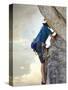 Young man rock climbing up a vertical cliff-null-Stretched Canvas