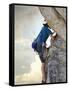 Young man rock climbing up a vertical cliff-null-Framed Stretched Canvas