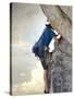 Young man rock climbing up a vertical cliff-null-Stretched Canvas