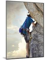 Young man rock climbing up a vertical cliff-null-Mounted Photographic Print