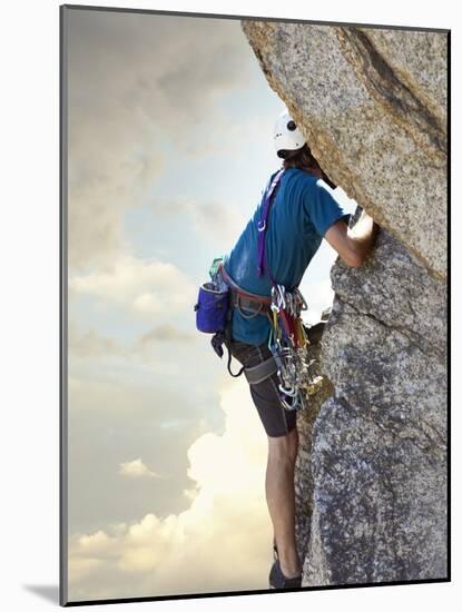 Young man rock climbing up a vertical cliff-null-Mounted Photographic Print