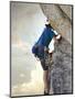 Young man rock climbing up a vertical cliff-null-Mounted Photographic Print