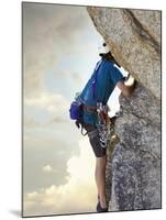 Young man rock climbing up a vertical cliff-null-Mounted Photographic Print