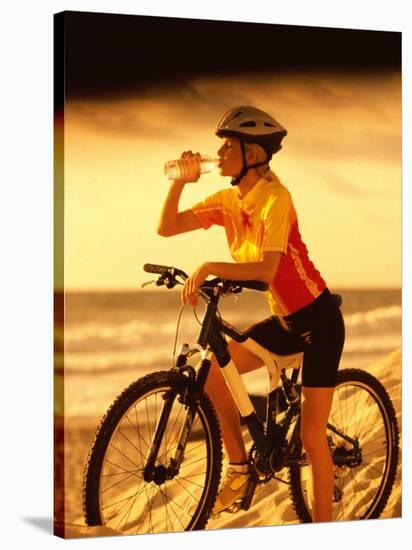 Young Woman Drinking Water Sitting on a Bicycle-null-Stretched Canvas