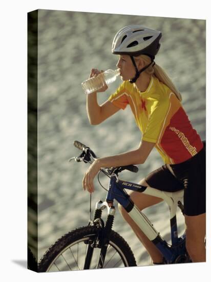 Young Woman Drinking Water While Sitting on a Bicycle-null-Stretched Canvas