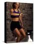 Young Woman Exercising on a Stationary Bike Checking her Heart Rate-null-Stretched Canvas