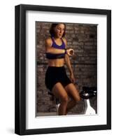 Young Woman Exercising on a Stationary Bike Checking her Heart Rate-null-Framed Photographic Print