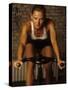 Young Woman Exercising on a Stationary Bike-null-Stretched Canvas