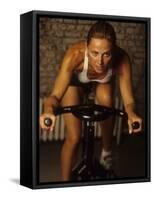 Young Woman Exercising on a Stationary Bike-null-Framed Stretched Canvas