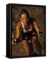 Young Woman Exercising on a Stationary Bike-null-Framed Stretched Canvas