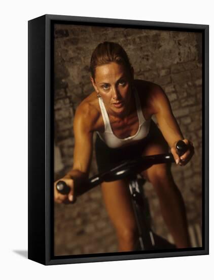 Young Woman Exercising on a Stationary Bike-null-Framed Stretched Canvas