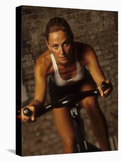 Young Woman Exercising on a Stationary Bike-null-Stretched Canvas