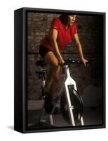 Young Woman Exercising on a Stationary Bike-null-Framed Stretched Canvas