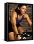 Young Woman Exercising on a Stationary Bike-null-Framed Stretched Canvas