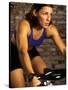 Young Woman Exercising on a Stationary Bike-null-Stretched Canvas