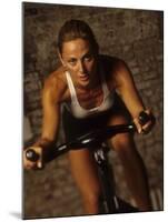 Young Woman Exercising on a Stationary Bike-null-Mounted Photographic Print