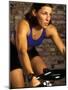 Young Woman Exercising on a Stationary Bike-null-Mounted Photographic Print