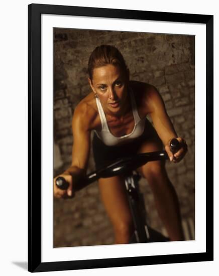 Young Woman Exercising on a Stationary Bike-null-Framed Photographic Print