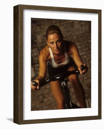 Young Woman Exercising on a Stationary Bike-null-Framed Photographic Print