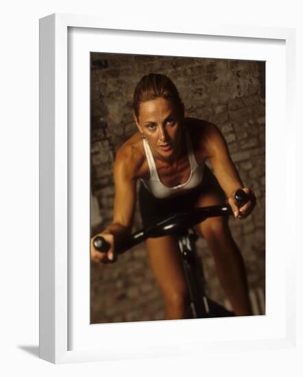 Young Woman Exercising on a Stationary Bike-null-Framed Photographic Print