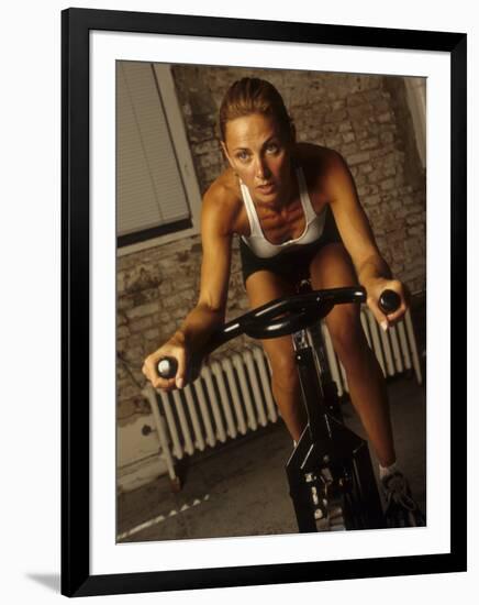 Young Woman Exercising on a Stationary Bike-null-Framed Photographic Print