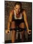 Young Woman Exercising on a Stationary Bike-null-Mounted Photographic Print