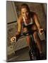 Young Woman Exercising on a Stationary Bike-null-Mounted Photographic Print