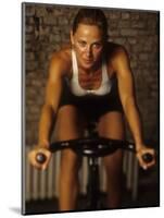 Young Woman Exercising on a Stationary Bike-null-Mounted Photographic Print