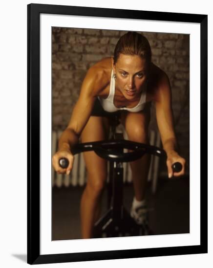 Young Woman Exercising on a Stationary Bike-null-Framed Photographic Print