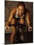 Young Woman Exercising on a Stationary Bike-null-Mounted Photographic Print