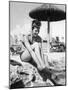 Young Woman in a Bikini Prepares to Go Snorkelling by Putting on Her Rubber Flippers-null-Mounted Photographic Print