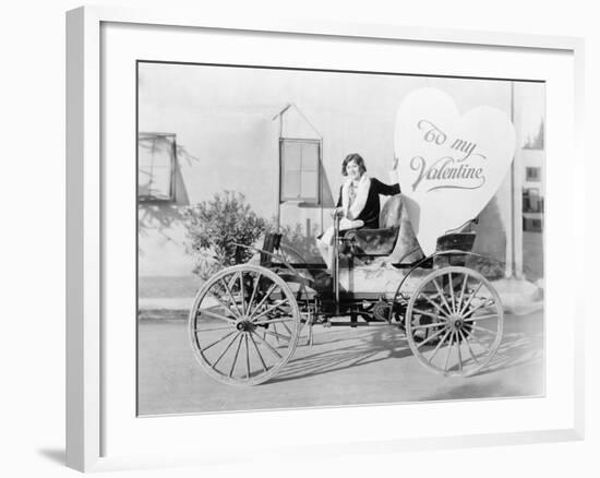 Young Woman Sitting on a Car Holding a Big Heart Shaped Sign-null-Framed Photo